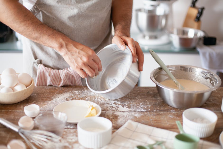 Baker sprinkling flour on fresh cake batter