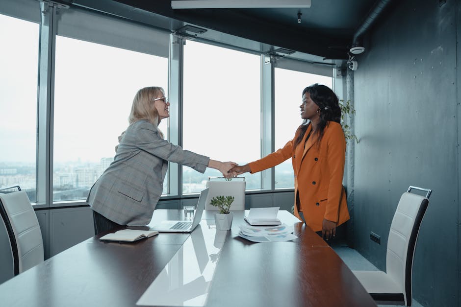 Corporate executives shaking hands with startup CEO in modern office