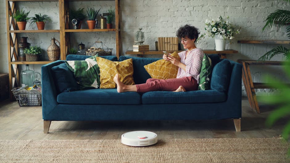 happy woman using smartphone with robot vacuum at home