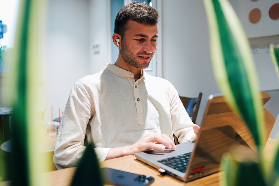 man wearing modern earbuds while working at cafe in Barcelona