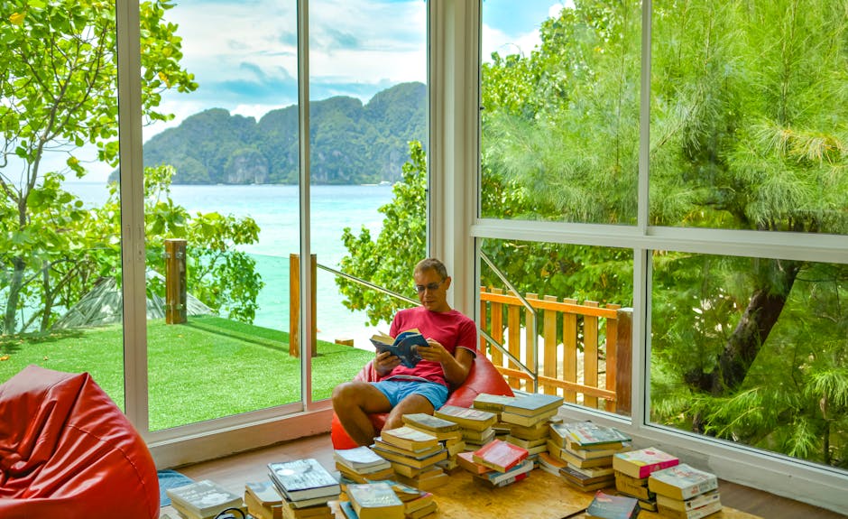 person reading book by window with scenic mountain view