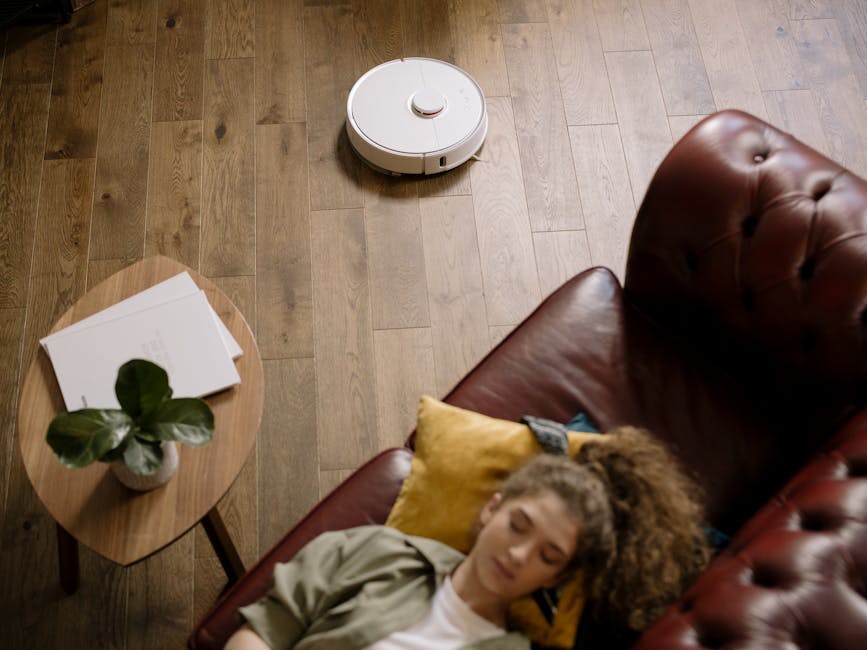 person relaxing on couch while robot vacuums