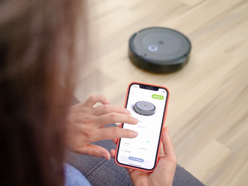 person using smartphone with smart vacuum app